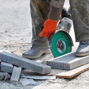 4704829-un-constructeur-tenir-une-scie-electrique-fonctionnelle-avec-une-lame-diamant-et-couper-des-blocs-de-granit-en-fond-du-lieu-de-travail-gros-plan-fond-flou-photo